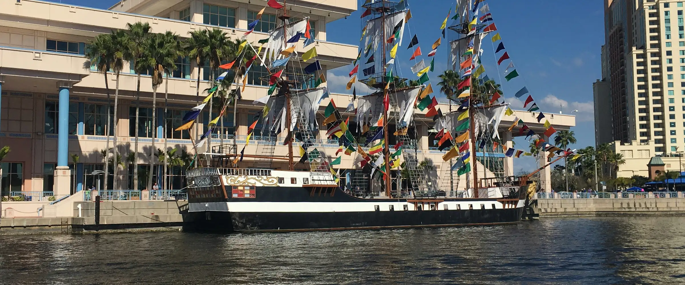 A tall ship docked by the Tampa Convention Center on the Hillsborough River